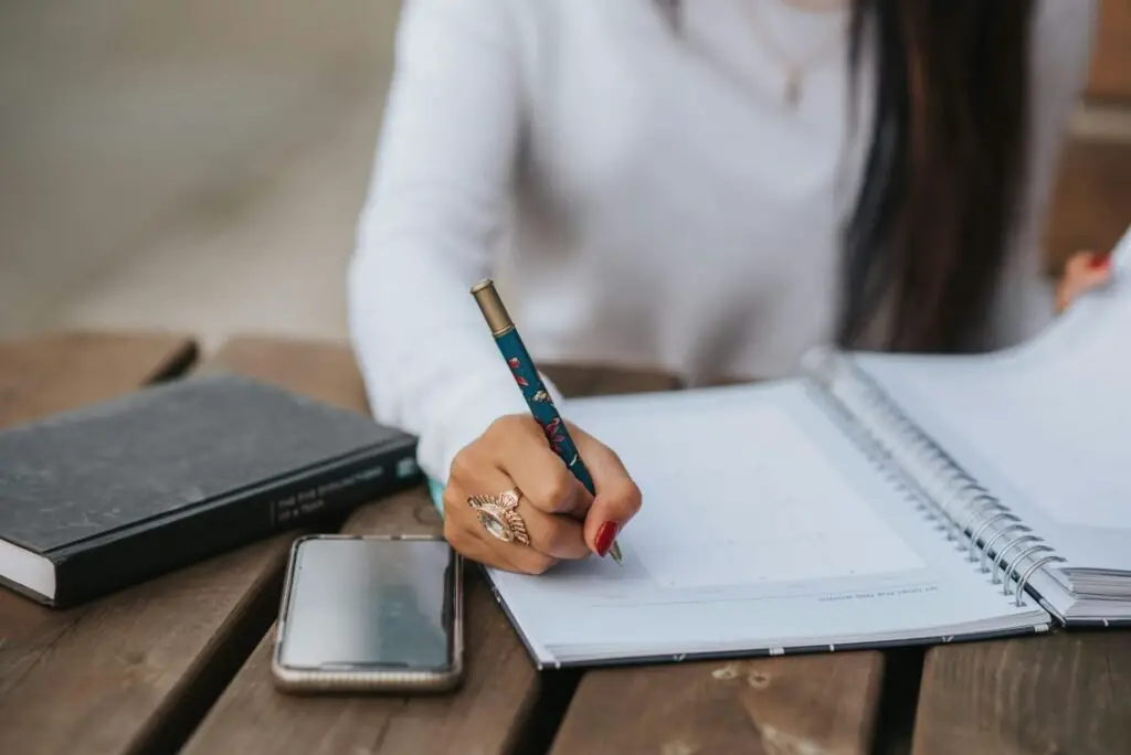 a girl writing daily goals on a journal