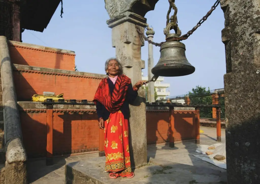 old women in traditional clothes ringing the bell